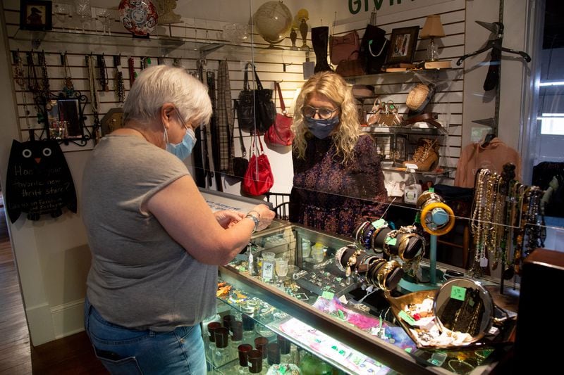 Karen Moore, (R), one of the officers at the Giving Tree Thrift Store in Chamblee, helps Karyl Boyd with a purchased Saturday, October 24, 2020.   STEVE SCHAEFER / SPECIAL TO THE AJC 