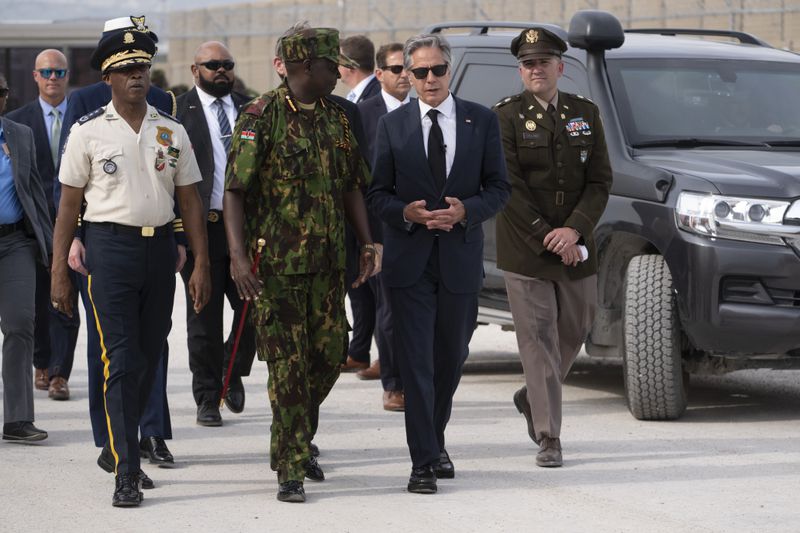 U.S. Secretary of State Antony Blinken, in sunglasses, and Commander of the Multinational Security Support Mission Commander Godfrey Otunge chat at the MSS base in Port-au-Prince, Haiti, Thursday, Sept. 5, 2024. (Roberto Schmidt/Pool photo via AP)