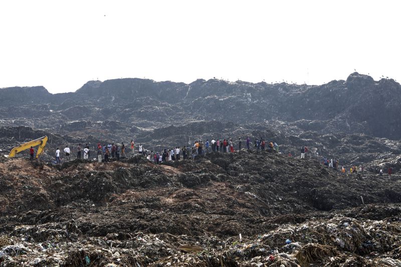 Onlookers watch as workers search for survivors at the site of a collapsed landfill in Kampala, Uganda, Sunday, Aug. 11, 2024. (AP Photo/Hajarah Nalwadda )