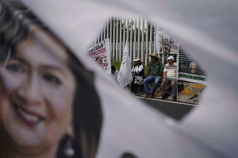 Government supporters sit outside Congress in favor of constitutional reform proposals that would make judges stand for election in Mexico City, Tuesday, Sept. 3, 2024. Their banner is against former presidential candidate Xochitl Galvez. (AP Photo/Felix Marquez)