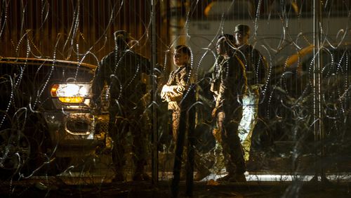 Texas Army National Guard members talk while patrolling behind razor wire on the banks of the Rio Grande in El Paso, Texas, seen from Ciudad Juarez, Mexico, late Thursday, Aug. 8, 2024. (AP Photo/Andres Leighton)