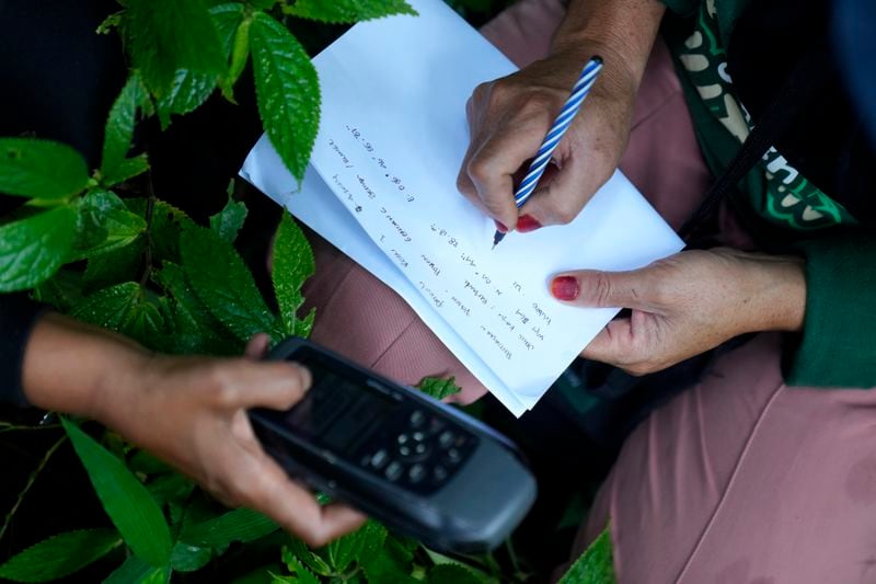 A ranger writes down a GPS-marked position during a forest patrol in Damaran Baru, Aceh province, Indonesia, Tuesday, May 7, 2024. The female-led group of forest rangers are defying social norms to lead patrols in the jungle to combat deforestation. (AP Photo/Dita Alangkara)
