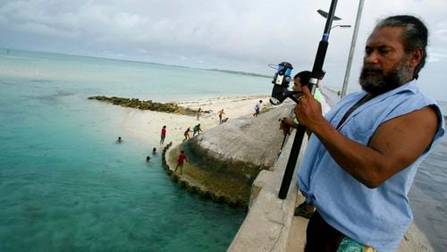 FILE - A man fishes on a bridge on Tarawa atoll, Kiribati, on March 30, 2004. (AP Photo/Richard Vogel, File)