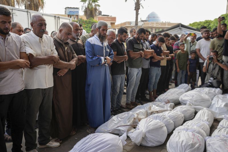 Palestinian mourners pray at the funeral for more than 15 people, including several children and women, killed in an Israeli strike, at Al-Aqsa Martyrs Hospital in Deir al-Balah, Gaza Strip, Saturday, Aug. 17, 2024. The strike hit a house and an adjacent warehouse sheltering displaced people at the entrance of the town of Zawaida, according to the hospital where the casualties were taken. (AP Photo/Abdel Kareem Hana)