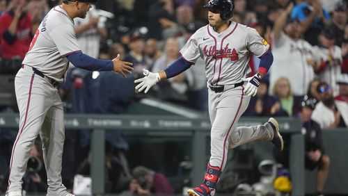 Atlanta Braves third base coach Matt Tuiasosopo, left, congratulates Ramón Laureano as he circles the bases after hitting a solo home run off Colorado Rockies relief pitcher Justin Lawrence in the seventh inning of a baseball game Friday, Aug. 9, 2024, in Denver. (AP Photo/David Zalubowski)