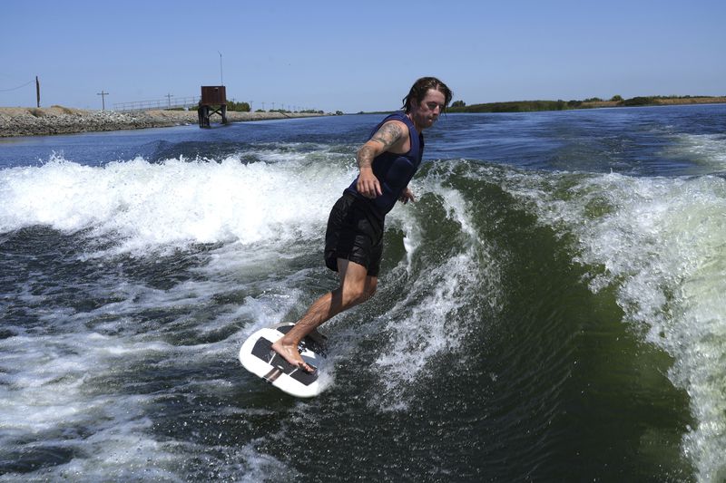 Grant Jeide wake surfs behind an electric sports boat made by California-based Arc Boats on the Sacramento-San Joaquin Delta near Bethel Island, Calif. on Wednesday, July 31, 2024. (AP Photo/Terry Chea)