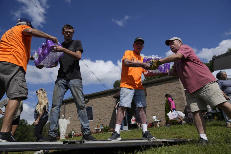 Volunteers unload cases of water and other donated supplies outside St. Michael the Archangel Catholic church in the aftermath of Hurricane Helene in Erwin, Tenn., on Thursday, Oct. 3, 2024. (AP Photo/Jeff Roberson)