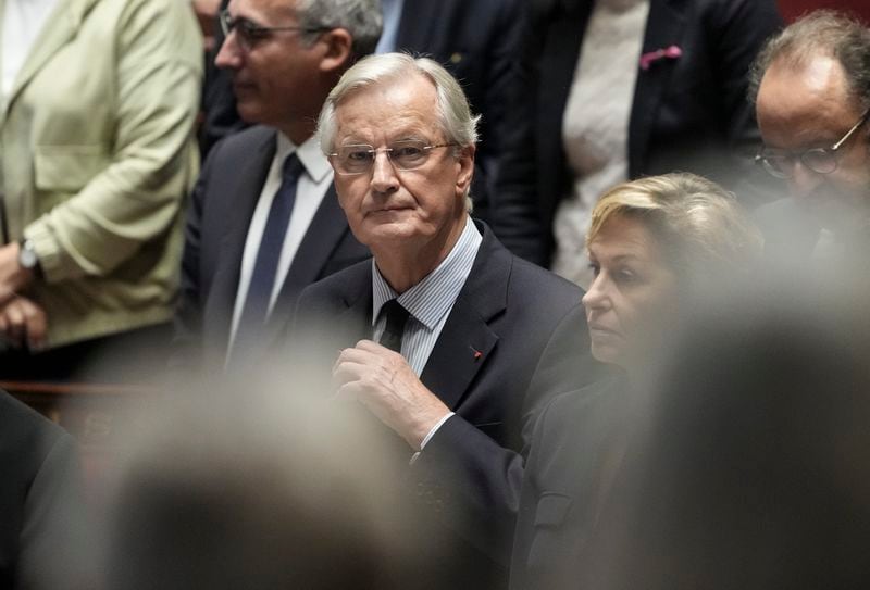 France's Prime Minister Michel Barnier adjust his tie prior to his speech at the National Assembly, in Paris, Tuesday, Oct. 1, 2024. (AP Photo/Thibault Camus)