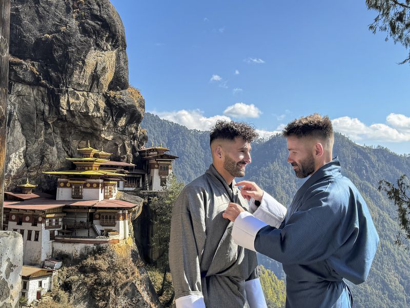 This 2024 photos shows Stefan Arestis, left, and Sebastien Chaneac at the Tiger’s Nest Monastery in Bhutan. The two have written a guide for LGBTQ+ Travelers, “Out in the World.” (The Nomadic Boys via AP)