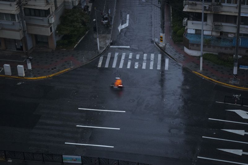 A motorist rides past a quiet road intersection as Typhoon Bebinca made landfall in Shanghai, China, Monday, Sept. 16, 2024. (Chinatopix Via AP)