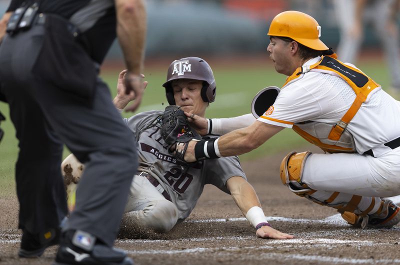 Tennessee catcher Cal Stark, right, tags out Texas A&M's Jackson Appel during the third inning of Game 1 of the NCAA College World Series baseball finals in Omaha, Neb., Saturday, June 22, 2024. (AP Photo/Rebecca S. Gratz)