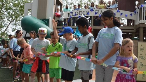 Several kids line up to break a paper chain to officially open the new PlayTown Suwanee playground at Town Center on Main Park. (Photo Courtesy of Curt Yeomans)