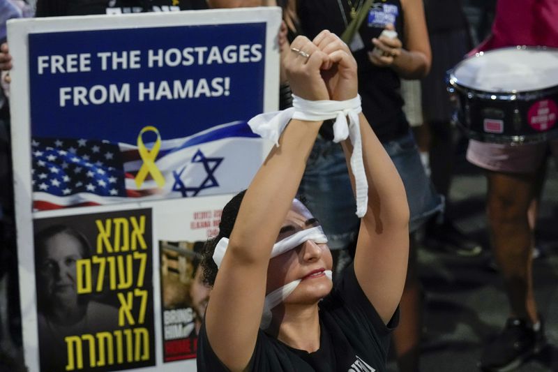 A woman wears a blindfold during a protest calling for a cease-fire deal and the immediate release of hostages held in Gaza by Hamas in Tel Aviv, Israel on Wednesday, Sept. 4, 2024. (AP Photo/Ariel Schalit)