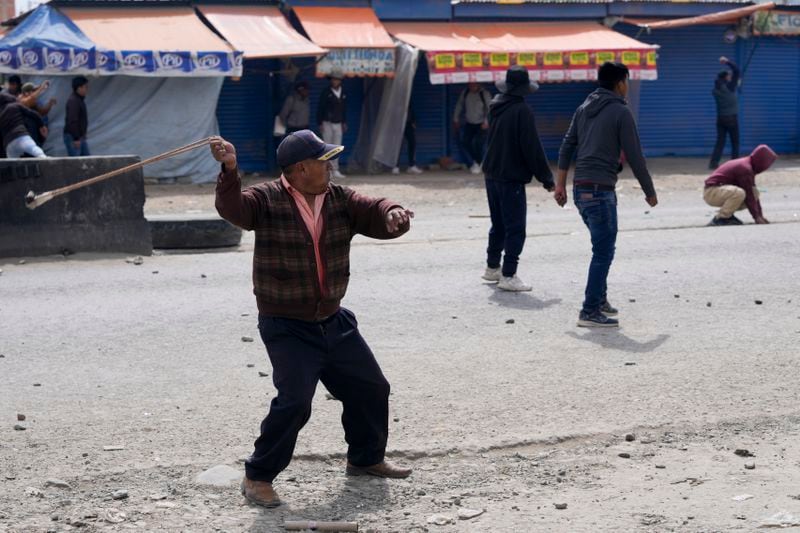 A supporter of former President Evo Morales, marching to La Paz to protest the government of current President Luis Arce, slings a rock while advancing toward Arce supporters in El Alto, Bolivia, Sunday, Sept. 22, 2024. (AP Photo/Juan Karita)