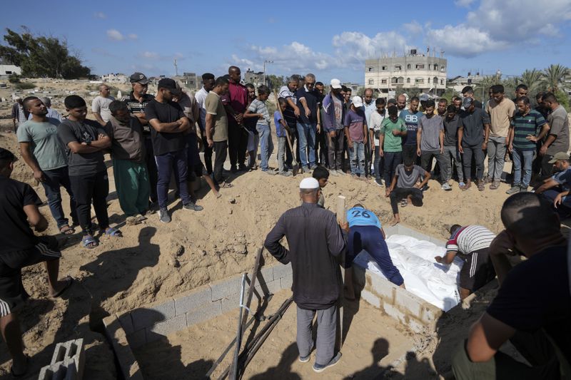 Palestinian grave digger Sa'di Baraka, center, oversees a burial in the cemetery in Deir al-Balah, Gaza Strip, Saturday, Aug. 10, 2024. (AP Photo/Abdel Kareem Hana)