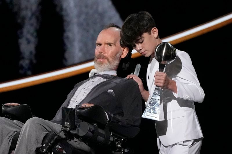 Steve Gleason, left, with his son Rivers, right, accept the Arthur Ashe Award for Courage at the ESPY awards on Thursday, July 11, 2024, at the Dolby Theatre in Los Angeles. (AP Photo/Mark J. Terrill)