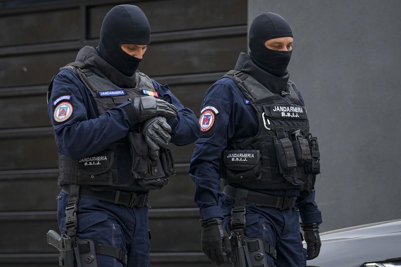 Gendarmes wearing balaclavas walk outside the residence of Andrew Tate during a police search raid, on the outskirts of Bucharest, Romania, Wednesday, Aug. 21, 2024. (AP Photo/Vadim Ghirda)