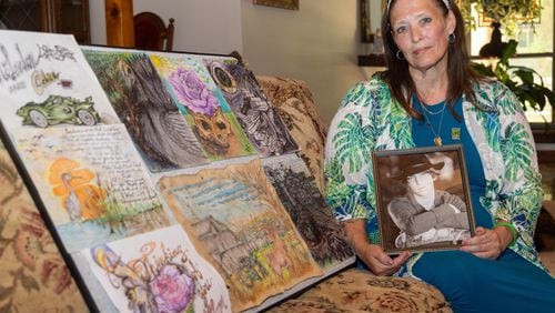 Dawn Mclendon sits beside some of her son Travis' artwork in her East Cobb home. She lost her son Travis, age 33, just before Mother's Day of 2023 to fentanyl poisoning. But before he left this world, he donated his liver to his mother and saved her life.  PHIL SKINNER FOR THE ATLANTA JOURNAL-CONSTITUTION