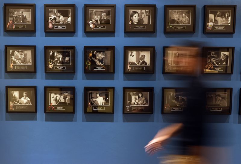 An employee blurs past a wall of photos featuring famous voice cast members from DreamWorks Animation films over the years, Wednesday, Sept. 25, 2024, at DreamWorks Animation in Glendale, Calif. (AP Photo/Chris Pizzello)