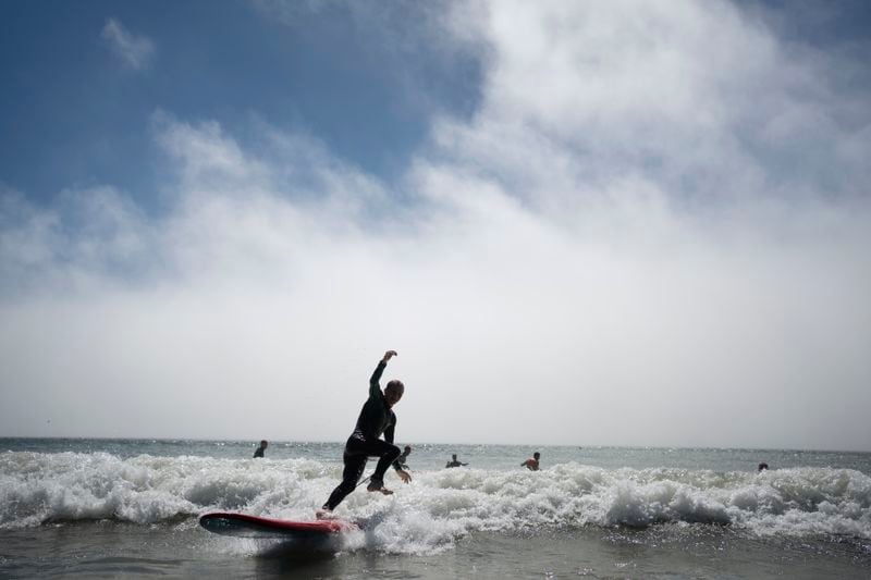 Surf Church member Zakharii Yarovyi, from Ukraine, surfs before a worship service in Matosinhos beach in the suburbs of Porto, Portugal on Sunday, Aug. 18, 2024. (AP Photo/Luis Andres Henao)