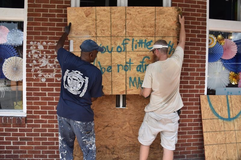 Employees Eric Young (left) and Erik Hare board up Twinkle, a jewelry and watches store in Savannah Historic District, ahead of Hurricane Dorian on Sept. 3. HYOSUB SHIN / HYOSUB.SHIN@AJC.COM