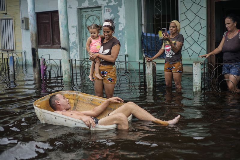 A man floats in a container on a street flooded by the passing of Hurricane Helene, in Batabano, Mayabeque province, Cuba, Thursday, Sept. 26, 2024. (AP Photo/Ramon Espinosa)