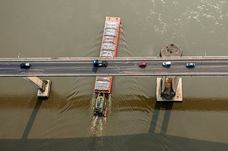 A tugboat pushes a barge under the Remanso bridge on the Paraguay River in Mariano R. Alonso, Paraguay, Monday, Sept. 9, 2024. Water levels have plunged to their lowest-ever level amid a drought, according to Paraguay's Meteorology and Hydrology Office. (AP Photo/Jorge Saenz)