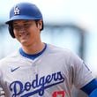 Los Angeles Dodgers' Shohei Ohtani smiles after reaching first base on a single off Colorado Rockies relief pitcher Seth Halvorsen in the eighth inning of a baseball game Sunday, Sept. 29, 2024, in Denver. (AP Photo/David Zalubowski)