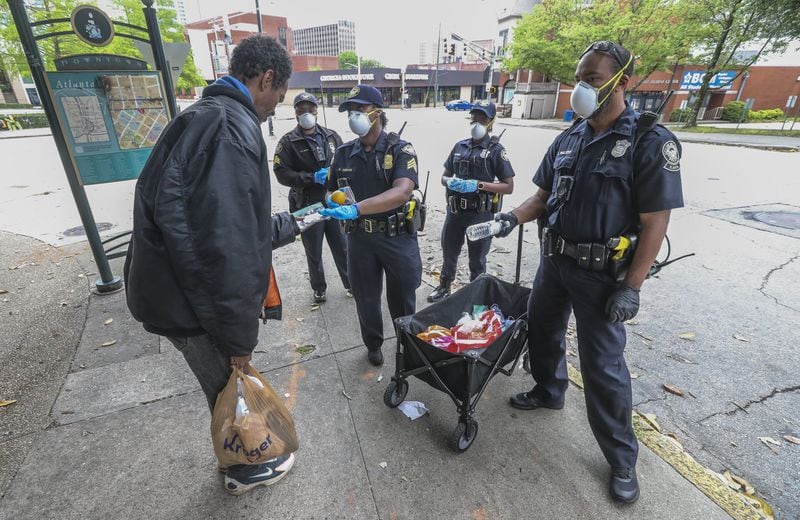 Atlanta Police Department officers distribute masks to the homeless at Hurt Park downtown on Friday, April 24, 2020. 