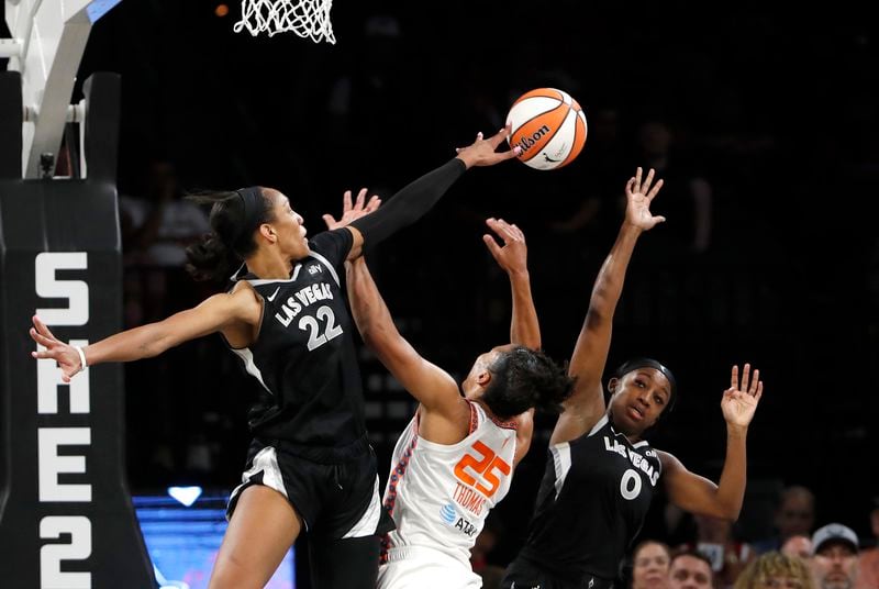 Connecticut Sun forward Alyssa Thomas (25) is fouled as she tries to shoot between Las Vegas Aces center A'ja Wilson (22) and guard Jackie Young (0) during the first half of an WNBA basketball game Sunday, Sept. 15, 2024, in Las Vegas. (Steve Marcus/Las Vegas Sun via AP)