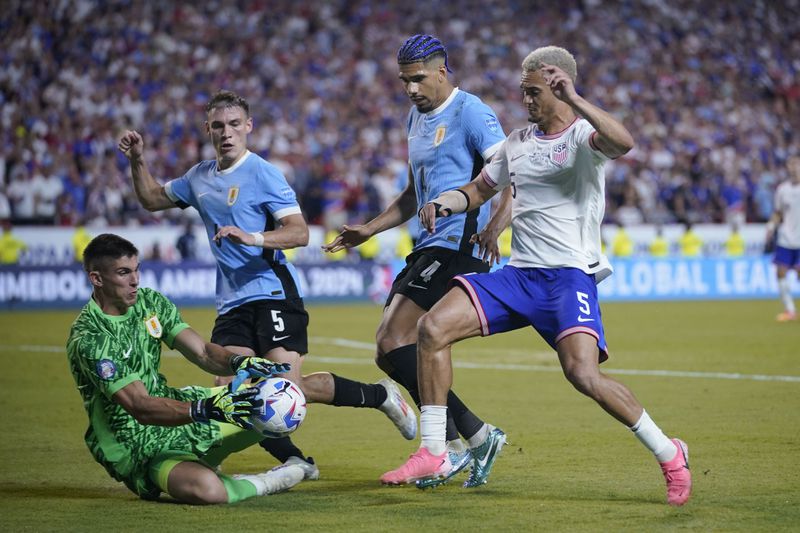 Uruguay's goalkeeper Sergio Rochet, left, blocks a shot by Antonee Robinson, right, of the United States, during a Copa America Group C soccer match, Monday, July 1, 2024, in Kansas City, Mo. (AP Photo/Ed Zurga)