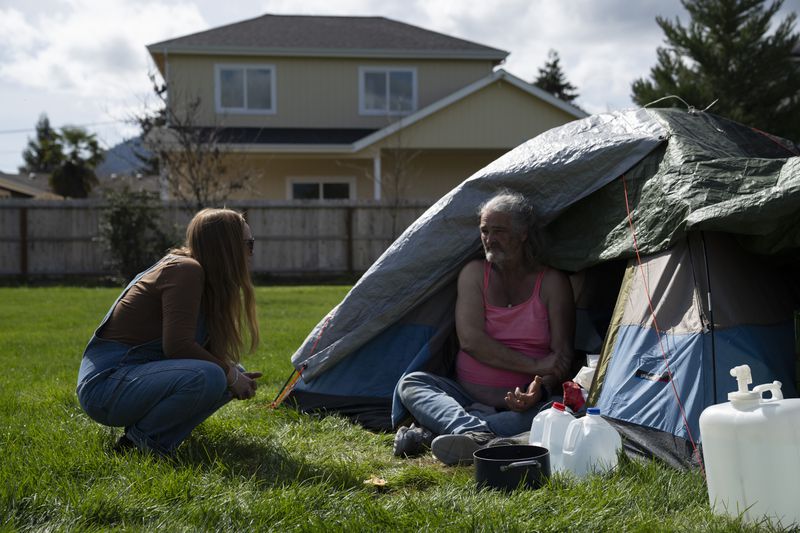FILE - Cassy Leach, a nurse who leads a group of volunteers who provide food, medical care and other basic goods to the hundreds of homeless people living in the parks, talks to Kimberly Marie, who is homeless and camping in Fruitdale Park on March 21, 2024, in Grants Pass, Ore. On Friday, June 28, the Supreme Court ruled that cities can enforce bans on homeless people sleeping outdoors in West Coast areas where shelter space is lacking. (AP Photo/Jenny Kane, File)