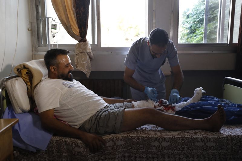 A Syrian nurse treats an man who was injured in the town of Masyaf, Syria, Monday, Sept. 9, 2024. Syrian state news agency SANA says that Israeli strikes hit several areas in central Syria Sunday night, damaging a highway in Hama province and sparking fires. (AP Photo/Omar Sanadiki)