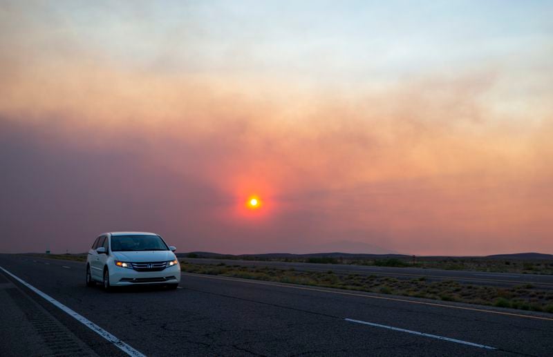 A car rides on the road to Roswell, N.M., as smoke from a wildfire partially blocks the sun near the village of Ruidoso, N.M., Tuesday, June 18, 2024. Thousands of southern New Mexico residents fled the mountainous village as a wind-whipped wildfire tore through homes and other buildings. (AP Photo/Andres Leighton)