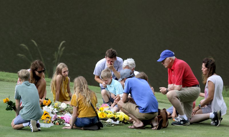 Mourners gather at a memorial for Gene Siller on Friday at the Pinetree Country Club. The country club's golf pro was shot and killed on the 10th hole when a suspected gunman drove onto the course and got stuck, officials said. Two other men were found dead in the bed of a truck. Bryan Rhoden, 23, was arrested Thursday in the triple homicide. (Christine Tannous / christine.tannous@ajc.com)