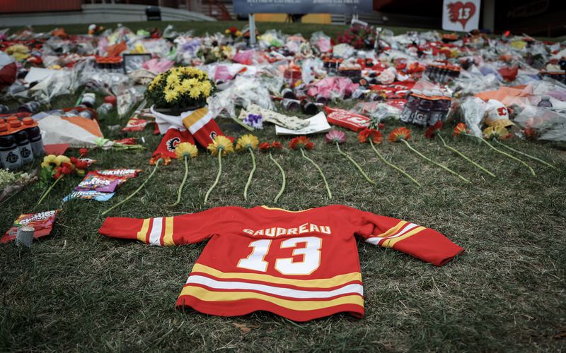 Flowers and memorabilia for former Calgary Flames player Johnny Gaudreau and his brother Matthew lie on the grass outside the Saddledome in Calgary, Alberta, Wednesday, Sept. 4, 2024. (Jeff McIntosh/The Canadian Press via AP)