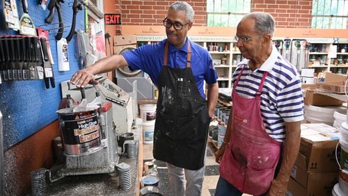 Father and son Thomas Portis (right) and Thomas Portis Jr.  show an over 60-year-old paint shaker at Southwest Paint and Decorating, Thursday, July 10, 2024 in Atlanta. The Southwest Paint and Decorating Center on Ralph David Abernathy Blvd. has remained open for five decades since Portis purchased the business. He and his family have kept it afloat through hardships over the years like the COVID-19 pandemic.(Hyosub Shin / AJC)