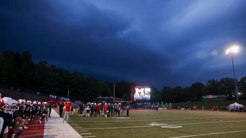 Storm clouds approach the stadium as the Milton defense huddles up against Buford in the first half at Milton High School, Friday, August 16, 2024, in Milton, Ga. (Jason Getz / AJC)
