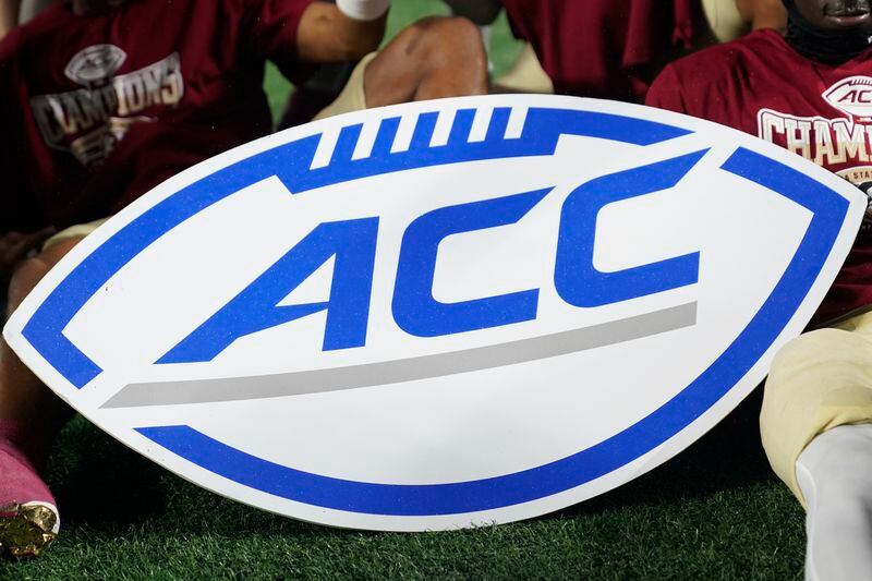 FILE - An Atlantic Coast Conference sign is displayed by Florida State players after the team's win over Louisville in the ACC championship NCAA college football game Dec. 2, 2023, in Charlotte, N.C. The NCAA and the nation's five biggest conferences have agreed to pay nearly $2.8 billion to settle a host of antitrust claims,a monumental decision that sets the stage for a groundbreaking revenue-sharing model that could start directing millions of dollars directly to athletes as soon as the 2025 fall semester. (AP Photo/Erik Verduzco, File)