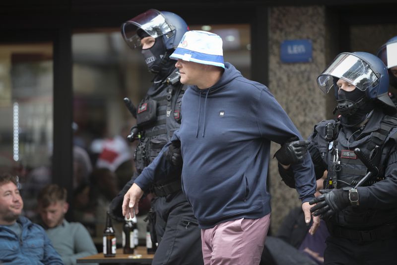 Police detain an England soccer fan ahead the Group C match between Serbia and England at the Euro 2024 soccer tournament in Gelsenkirchen, Germany, Sunday, June 16, 2024. (AP Photo/Markus Schreiber)