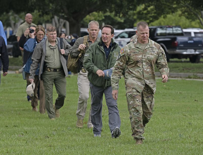 Louisiana National Guard Maj. Gen. Thomas C. Friloux, right, leads Louisiana Gov. Jeff Landry and Louisiana State Police Col Robert P. Hodges to a helicopter for an aerial tour of damage from Hurricane Francine, Thursday, Sept. 12, 2024, in Baton Rouge, La., (Hilary Scheinuk/The Advocate via AP)