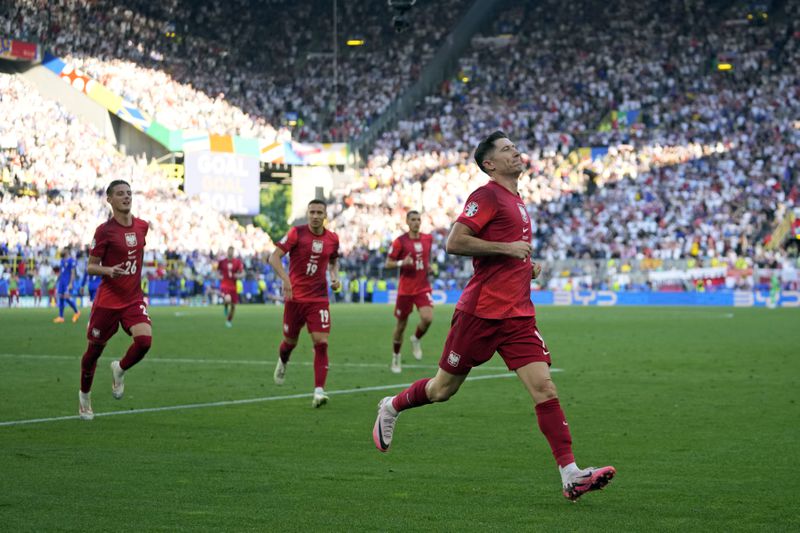 Poland's Robert Lewandowski, right, celebrates with teammates after scoring during a Group D match between the France and Poland at the Euro 2024 soccer tournament in Dortmund, Germany, Tuesday, June 25, 2024. (AP Photo/Sergei Grits)
