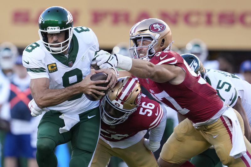 New York Jets quarterback Aaron Rodgers tries to scramble from San Francisco 49ers defensive end Leonard Floyd (56) and defensive end Nick Bosa, right, before being sacked by Floyd during the first half of an NFL football game in Santa Clara, Calif., Monday, Sept. 9, 2024. (AP Photo/Godofredo A. Vásquez)