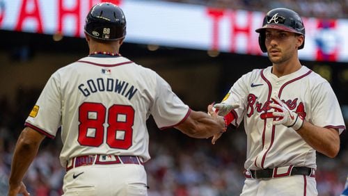 Atlanta Braves' Matt Olson, right, slaps hands with first base coach Tom Goodwin, left, after hitting a single to right field in the eighth inning of a baseball game against the Kansas City Royals, Sunday, Sept. 29, 2024, in Atlanta. (AP Photo/Jason Allen)