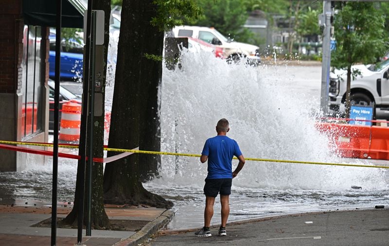 Joe Greene watches a water main break at the corner of the corner of 11th Street and West Peachtree Street, Saturday, June 1, 2024, in Atlanta. A water main that ruptured, causing thousands to lose access to water around Atlanta, was repaired Saturday morning but water may take several hours to be restored. (Hyosub Shin / AJC)