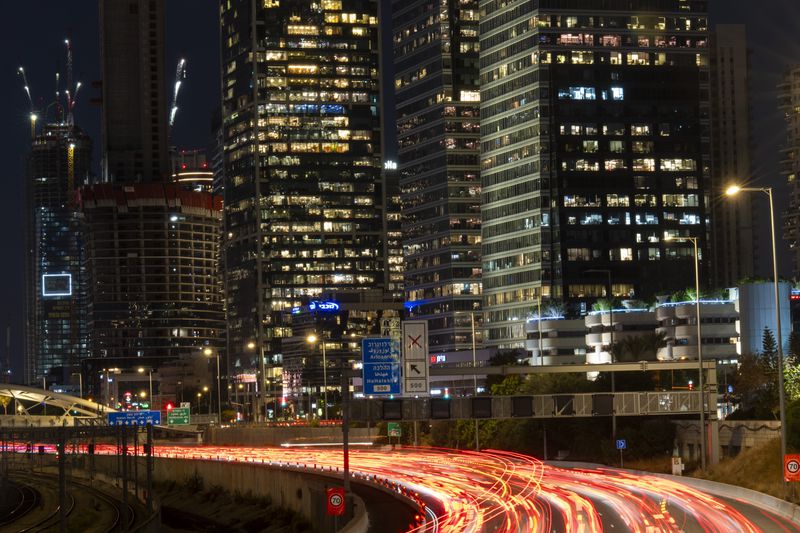 In this photo taken with a long exposure, traffic moves slowly in Tel Aviv, Israel, Wednesday, Aug. 14, 2024. Israel's economy is suffering from the nearly 11-month war with Hamas, as its leaders grind ahead with its offensive in Gaza that threatens to escalate into a wider conflict. (AP Photo/Ariel Schalit)