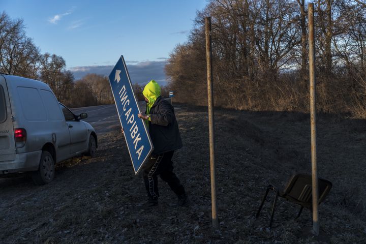 A Ukrainian worker removes a road sign to complicate Russian military navigation in Kalynivka, Ukraine, Feb. 26, 2022. (Brendan Hoffman/The New York Times)