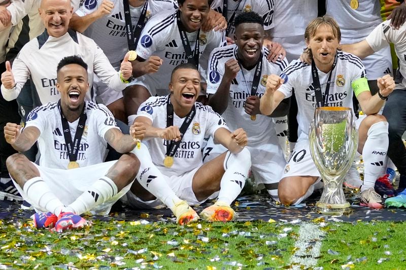 Real Madrid's Eder Militao, Kylian Mbappe, Vinicius Junior, and Luka Modric pose with the trophy after winning the UEFA Super Cup Final soccer match between Real Madrid and Atalanta at the Narodowy stadium in Warsaw, Poland, Wednesday, Aug. 14, 2024. Real Madrid won 2-0. (AP Photo/Darko Bandic)