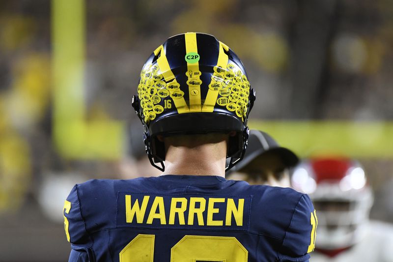 Michigan quarterback Davis Warren prepares to hike the ball against Fresno State in the second half of an NCAA college football game, Saturday, Aug. 31, 2024, in Ann Arbor, Mich. The green dot on Warren's helmet illustrates that wireless communication is allowed between a coach and a single player on each side of the ball. (AP Photo/Jose Juarez) (AP Photo/Jose Juarez)