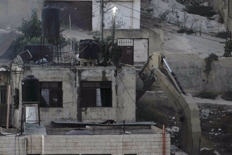 EDS NOTE: GRAPHIC CONTENT - Israeli soldiers look over a rooftop in the West Bank town of Qatabiya near two corpses. The Israeli army raided the northern West Bank town on Thursday, as violence surges across the Israeli-occupied territory. Thursday, Sept.19, 2024. (AP Photo/Majdi Mohammed)